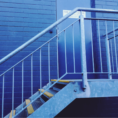 Commercail property risk - close-up of emergency exit and stairs against blue wall